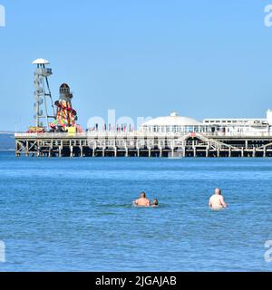 Bournemouth, Dorset, Inghilterra, Regno Unito, 9th luglio 2022, Meteo. Onda termica. La gente arriva alla spiaggia prima delle 9 del sabato mattina. Le temperature raggiungeranno i 20s alti nel pomeriggio sotto il sole parete-parete. Nuotatore in mare vicino al molo. Credit: Paul Biggins/Alamy Live News Foto Stock