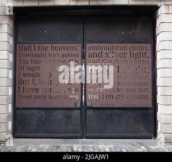 Una poesia di W B Yeats fa parte dell'arte di strada che adorna un cancello come parte degli edifici del tribunale commerciale di Belfast nel quartiere della Cattedrale Foto Stock