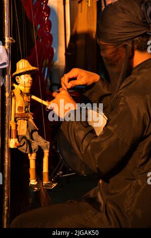 Il burattinaio professionista thailandese o il padrone del burattini manipolano suonare il giocattolo antico del burattini o la marionetta antica sul palco mostrano la gente in Nig Foto Stock