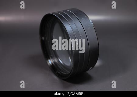 Quattro filtro obiettivo da primo piano collegato insieme e impostato su uno sfondo nero Foto Stock