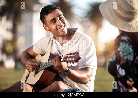Cantare su tutte le cose che amo di te. Un giovane che suona una chitarra mentre si fa un picnic con la sua ragazza. Foto Stock