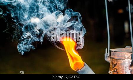 Un primo piano su un collo d'oca del bollitore con fuoco e vapore in uscita dal foro Foto Stock