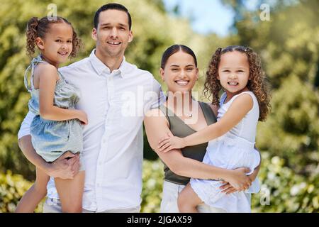 La famiglia è amore, sorride e tutto ciò che c'è nel mezzo. Ritratto di una giovane e felice famiglia che si gode una divertente giornata al parco. Foto Stock