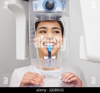 Come perfetto i miei denti guardare. Una giovane donna che usa una macchina a raggi X in un ufficio dentistico. Foto Stock