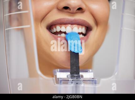 Il mio dentista ha detto morso giù. Una giovane donna che usa una macchina a raggi X in un ufficio dentistico. Foto Stock