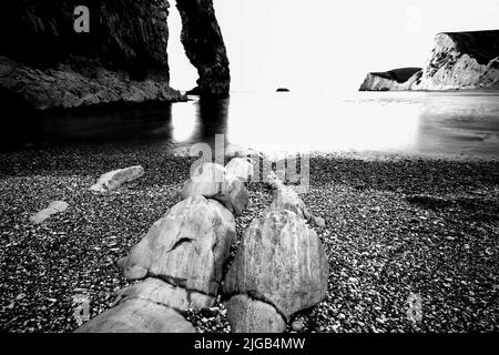 Una riva del mare e una roccia in bianco e nero Foto Stock