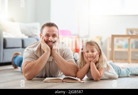 Espandendo la nostra mente con una certa lettura. Un padre e una figlia giovani che leggono un libro insieme nel paese. Foto Stock