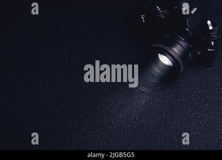 vecchia macchina fotografica con un raggio di luce dall'obiettivo nel fumo su uno sfondo nero Foto Stock