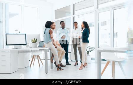 Le nostre riunioni mattutine sono produttive. Un gruppo di uomini d'affari che hanno una riunione in un ufficio moderno al lavoro. Foto Stock