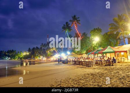 Caffè, ristoranti e nightclub sulla riva dell'Oceano Indiano in Sri Lanka di notte Foto Stock