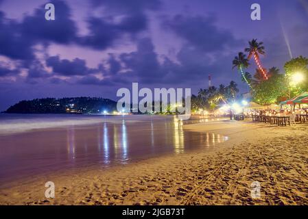 Caffè, ristoranti e nightclub sulla riva dell'Oceano Indiano in Sri Lanka di notte Foto Stock