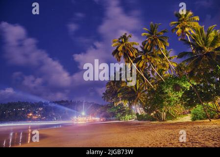 Caffè, ristoranti e nightclub sulla riva dell'Oceano Indiano in Sri Lanka di notte Foto Stock