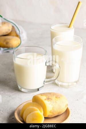 Bicchieri con latte di patate vegano e tuberi di patate su fondo concreto. Bevanda sana priva di lattosio. Latte vegetale. Impianto a base di latte sostitutivo. Selezionare Foto Stock