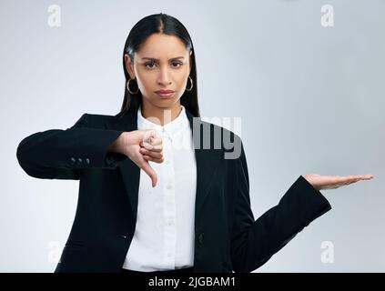 La felicità non è solo in possesso di denaro: Una donna commerciale con i pollici che mostra i pollici su uno sfondo grigio. Foto Stock