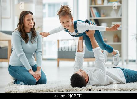 Volare in alto con papà. Una giovane famiglia che gioca insieme a casa. Foto Stock