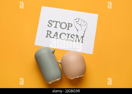 Figurine di uccelli e foglio di carta con testo STOP RAZZISMO su sfondo a colori Foto Stock