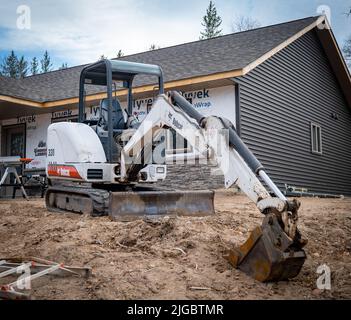 CROW WING CO, MN - 5 MAGGIO 2022: Miniescavatore Bobcat con cingoli per minipale, si siede sullo sporco di fronte a un nuovo cantiere di costruzione. Foto Stock