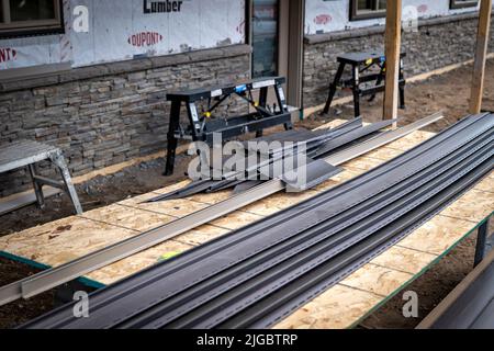 CROW WING CO, MN - 5 MAGGIO 2022: Le sezioni di vinil Siding che giacciono su un pezzo di compensato saranno presto installate sulle pareti esterne di un nuovo costrutto domestico Foto Stock