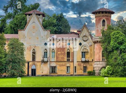 ITALIA, MIRADOLO - CIRCA AGOSTO 2020: Castello di design gotico situato in un giardino all'italiana, pieno di mistero, con luce del tramonto. Foto Stock