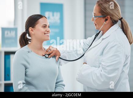 Posso dire che il trattamento sta funzionando bene per lei: Un medico che esamina un paziente con uno stetoscopio durante una consultazione in una clinica. Foto Stock
