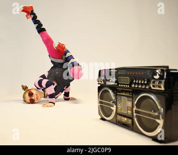 bambina in una posizione di breakdance difficile con un boombox Foto Stock