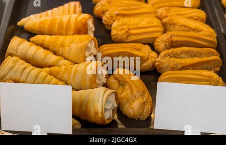 Pasticceria, tubetti con panna ed eclarie sono sul bancone in una deliziosa pasticceria. Foto Stock