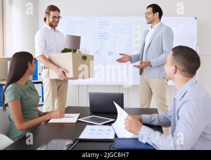 Abbiamo aspettato tutta la settimana per unirvi a noi. Un bel giovane uomo d'affari in piedi e introdurre un nuovo dipendente durante una riunione in ufficio. Foto Stock