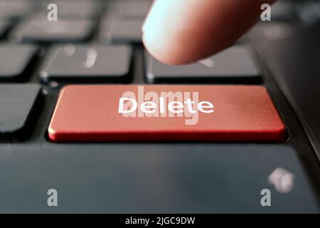 dito maschio premendo il tasto rosso cancella tastiera nera Foto Stock