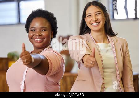 Il cliente ha sempre ragione. Ritratto ritagliato di due attraenti giovani imprenditori gesturing thumbs gesturing in piedi nel loro deposito. Foto Stock