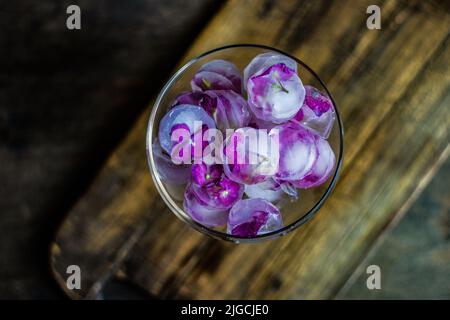 Bicchiere con fiori viola di ortangea cubetti di ghiaccio come rinfrescante bevanda estiva concetto Foto Stock