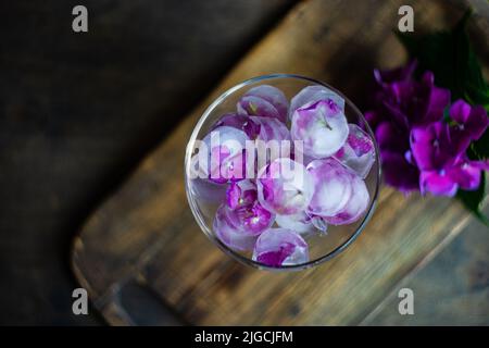 Bicchiere con fiori viola di ortangea cubetti di ghiaccio come rinfrescante bevanda estiva concetto Foto Stock