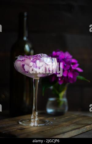 Bicchiere con fiori viola di ortangea cubetti di ghiaccio come rinfrescante bevanda estiva concetto Foto Stock
