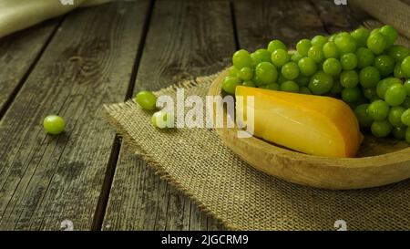 formaggio rustico e uva verde su un tavolo di legno in una fattoria Foto Stock