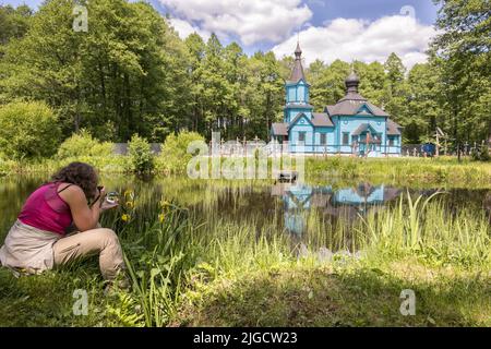 Una donna prende foto di blu, legno chiesa ortodossa. Podlasie. Podlachia. La Polonia, l'Europa. La regione è chiamato Podlasko o Podlasze Foto Stock