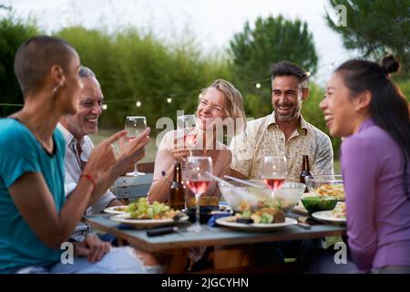 Felice uomini e donne di mezza età tostando cibo sano al pic-nic fattoria - concetto di stile di vita con amici allegri divertirsi insieme nel pomeriggio Foto Stock