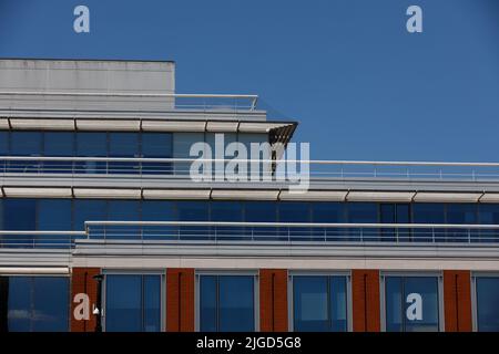 Particolare del tetto e dell'ultimo piano di un edificio moderno con doghe e ringhiere solari orizzontali e cornici verticali delle finestre e dettagli in mattoni Foto Stock