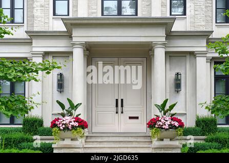 Ingresso della casa con colonne circondate da vasi di fiori Foto Stock