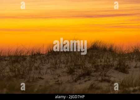 Il cielo brilla mentre il sole tramonta oltre una duna di sabbia al Gulf Island National Seashore vicino Pensacola, Florida, in una foto composita. Foto Stock