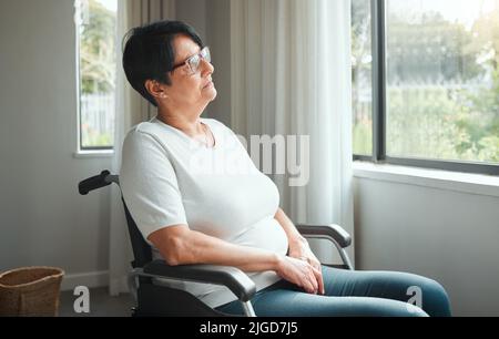 Im impaurito ive visto tutti i giorni migliori. Una donna anziana godendo la vista dalla sua finestra. Foto Stock