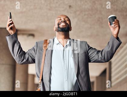 Un uomo d'affari che si sente favoloso e pronto a affrontare la giornata. Un uomo d'affari che si acclama mentre usa il suo smartphone. Foto Stock