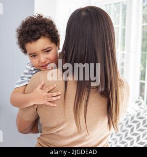 Un bambino ha bisogno di tutto il comfort che può ottenere, una madre che abbraccia il suo figlio triste a casa. Foto Stock