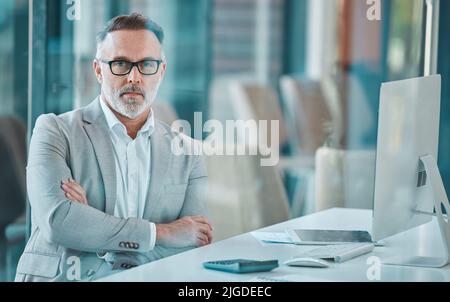 Nell'ufficio sono costruite grandi aziende, un uomo d'affari maturo seduto su una scrivania al lavoro. Foto Stock