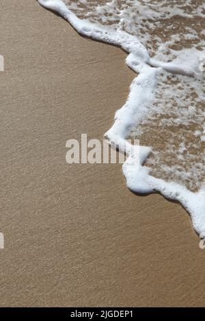 Un'onda rotola sulla sabbia in spiaggia. Spazio per aggiungere il proprio testo. Foto Stock