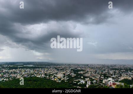 La pioggia riempì le nuvole monsoniche sopra una città nel sud dell'India Foto Stock