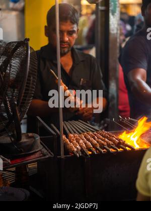 Mumbai, India - 1 maggio 2022 : il venditore musulmano maschio che cucina vende gli alimenti halal ed i Kabab dallo stallo stradale al mercato notturno nel mese santo del Ramadan. Foto Stock