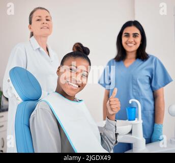 Ho i migliori dentisti, una giovane donna nel suo ufficio dentistico che dà i pollici in su. Foto Stock