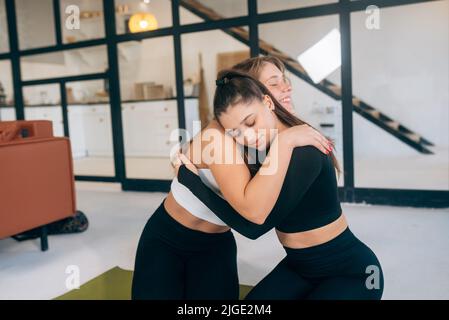 Due amiche si abbracciano dopo lo yoga Foto Stock