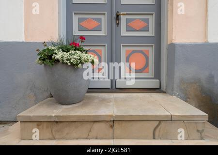 Tallinn, Estonia. Luglio 2022. Un vaso di fiori di fronte alla porta d'ingresso di una tipica casa del centro storico nel centro della città Foto Stock