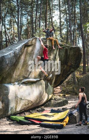 Il giovane atletico sta saltando per la tenuta superiore nel problema famoso e duro del dyno boulder denominato 'rainbow Rocket - 8a'. Fontainebleau, Francia, Europa. Foto Stock