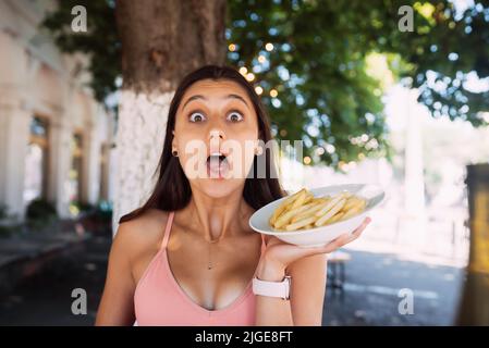 Le giovani donne tengono patatine fritte su piatti bianchi. Street cafe Foto Stock